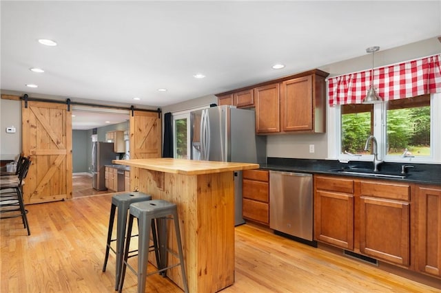 219 Fenner Hill Rd, Hopkinton, RI 02832 - kitchen featuring stainless steel appliances, a barn door, butcher block counters, a kitchen bar, and light wood-style floors