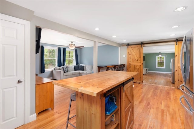219 Fenner Hill Rd, Hopkinton, RI 02832 - kitchen featuring butcher block counters, a barn door, a breakfast bar area, light wood-type flooring, and freestanding refrigerator