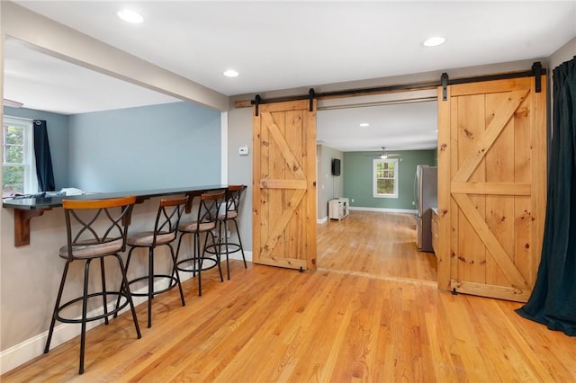 219 Fenner Hill Rd, Hopkinton, RI 02832 - kitchen featuring a barn door, freestanding refrigerator, light wood-style flooring, a kitchen bar, and radiator