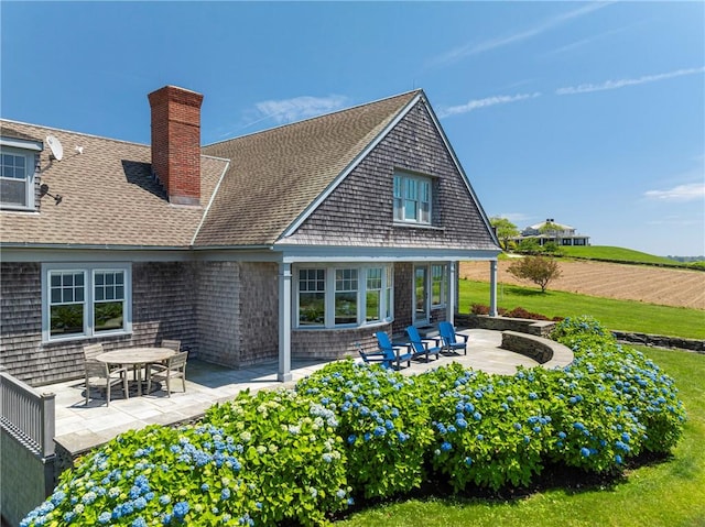 17 Ferolbink Way, Little Compton, RI 02837 - rear view of house featuring a patio, roof with shingles, a chimney, and a lawn