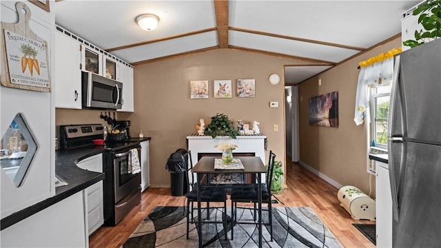 245 Manton St, Pawtucket, RI 02861 - kitchen featuring stainless steel appliances, dark countertops, light wood-style flooring, white cabinets, and vaulted ceiling