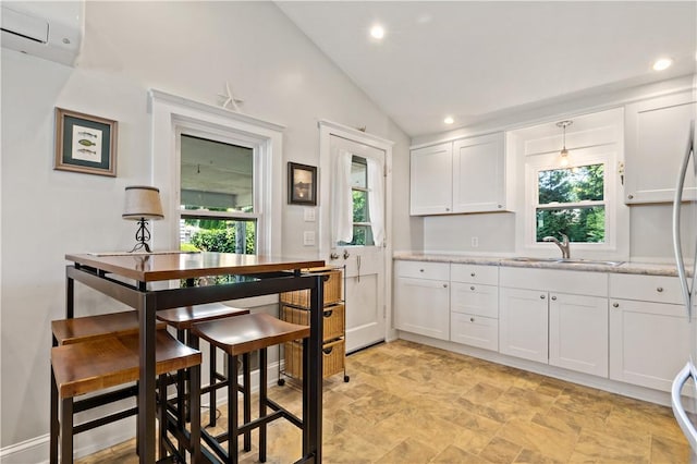 55 Wayland Trl, Narragansett, RI 02882 - kitchen with a wall unit AC, white cabinets, vaulted ceiling, recessed lighting, and stone finish flooring