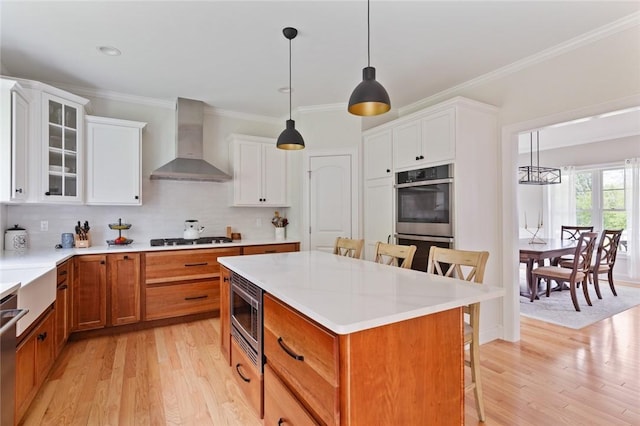 25 Kristin Dr, Cranston, RI 02921 - kitchen with wall chimney exhaust hood, appliances with stainless steel finishes, a breakfast bar area, light wood-type flooring, and a kitchen island