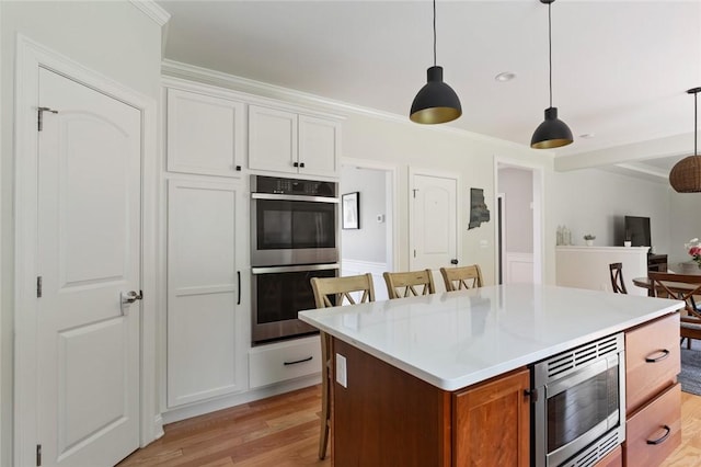25 Kristin Dr, Cranston, RI 02921 - kitchen with appliances with stainless steel finishes, light wood-type flooring, a breakfast bar, ornamental molding, and white cabinetry