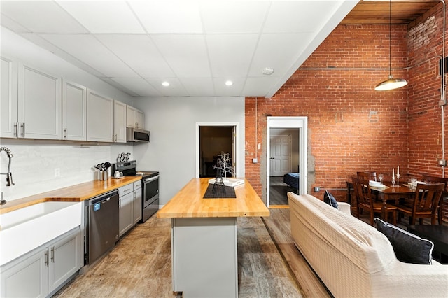 1117 Douglas Ave Unit 124, North Providence, RI 02904 - kitchen featuring butcher block countertops, stainless steel appliances, recessed lighting, brick wall, and decorative light fixtures