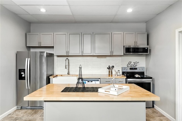 1117 Douglas Ave Unit 124, North Providence, RI 02904 - kitchen with appliances with stainless steel finishes, gray cabinetry, butcher block counters, a drop ceiling, and decorative backsplash