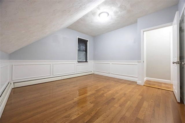 193 Howell St Unit 3, Providence, RI 02906 - additional living space with lofted ceiling, wood finished floors, a baseboard heating unit, a textured ceiling, and wainscoting