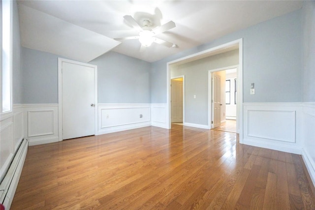 193 Howell St Unit 3, Providence, RI 02906 - spare room featuring a baseboard radiator, a wainscoted wall, a ceiling fan, light wood-style floors, and a decorative wall