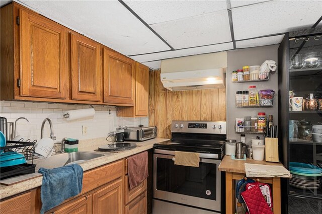 236 Vermont Ave, Providence, RI 02905 - kitchen with stainless steel electric stove, range hood, light countertops, brown cabinetry, and decorative backsplash