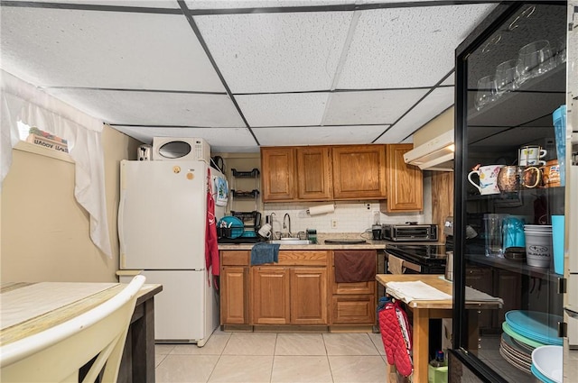 236 Vermont Ave, Providence, RI 02905 - kitchen featuring freestanding refrigerator, brown cabinets, light tile patterned floors, a drop ceiling, and backsplash