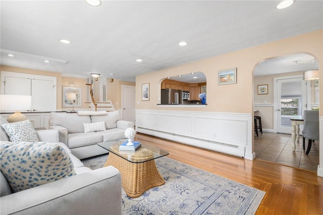 57 Hillside Rd, Lincoln, RI 02865 - living area featuring a baseboard heating unit, arched walkways, recessed lighting, wood finished floors, and a wainscoted wall
