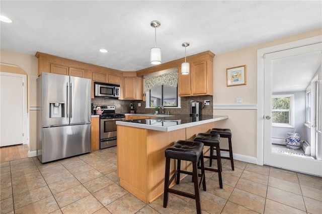 57 Hillside Rd, Lincoln, RI 02865 - kitchen featuring stainless steel appliances, a peninsula, decorative backsplash, a breakfast bar area, and decorative light fixtures