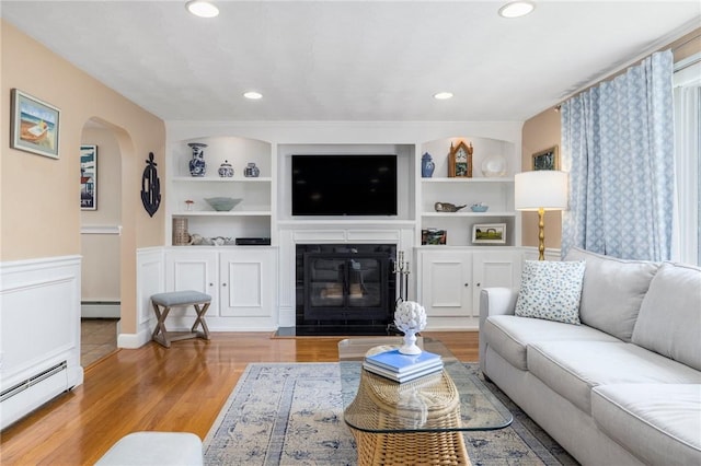 57 Hillside Rd, Lincoln, RI 02865 - living area featuring a baseboard heating unit, built in features, arched walkways, wood finished floors, and recessed lighting