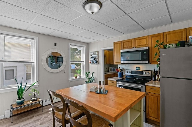 57 Maple Ave, Johnston, RI 02919 - kitchen with appliances with stainless steel finishes, light wood finished floors, a paneled ceiling, brown cabinetry, and a baseboard radiator