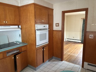 10 Jesse Davis Ln, Barrington, RI 02806 - kitchen featuring oven, wallpapered walls, baseboard heating, brown cabinets, and a wainscoted wall
