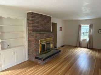 10 Jesse Davis Ln, Barrington, RI 02806 - unfurnished living room with light wood-style flooring, a fireplace, and built in features