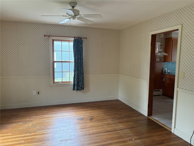 10 Jesse Davis Ln, Barrington, RI 02806 - empty room with wallpapered walls, wainscoting, ceiling fan, light wood-style floors, and a baseboard heating unit