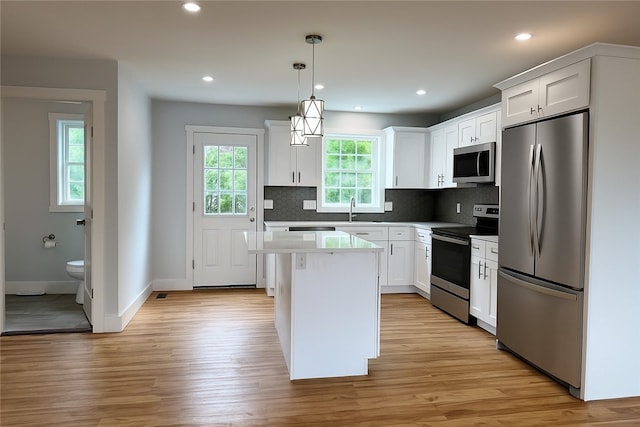 5 Crawford St, West Warwick, RI 02893 - kitchen featuring appliances with stainless steel finishes, light wood-style flooring, a center island, tasteful backsplash, and white cabinets