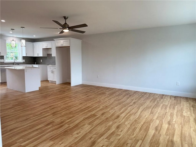 5 Crawford St, West Warwick, RI 02893 - kitchen with light wood-style floors, a center island, ceiling fan, white cabinets, and open floor plan