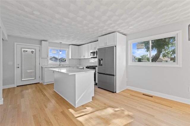 3 Riverview Ave, Westerly, RI 02891 - kitchen with appliances with stainless steel finishes, tasteful backsplash, light countertops, white cabinetry, and a kitchen island
