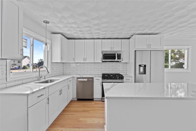 3 Riverview Ave, Westerly, RI 02891 - kitchen with appliances with stainless steel finishes, white cabinetry, light stone countertops, pendant lighting, and backsplash