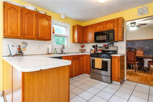 65 Jeri Lynn Cir, Warwick, RI 02886 - kitchen with black microwave, stainless steel gas range oven, a peninsula, light countertops, and brown cabinets