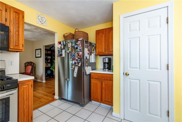 65 Jeri Lynn Cir, Warwick, RI 02886 - kitchen with stainless steel appliances, light countertops, brown cabinetry, and light tile patterned floors