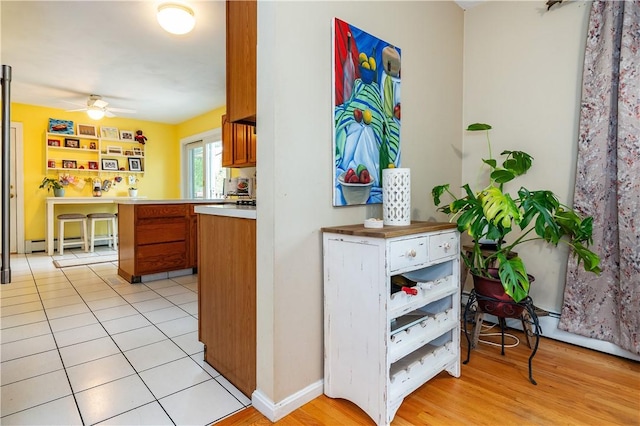 65 Jeri Lynn Cir, Warwick, RI 02886 - kitchen featuring brown cabinetry, a ceiling fan, light countertops, light wood finished floors, and a baseboard radiator