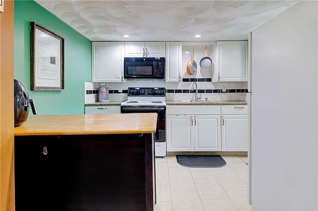 73 Fessenden St, Warwick, RI 02886 - kitchen with black microwave, electric stove, light tile patterned floors, white cabinets, and recessed lighting