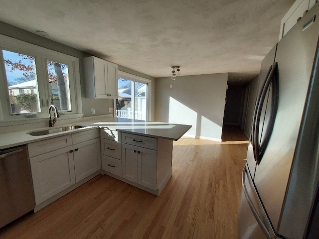 16 Fyffe Ave, Cranston, RI 02920 - kitchen with appliances with stainless steel finishes, a peninsula, white cabinets, light wood-type flooring, and light countertops