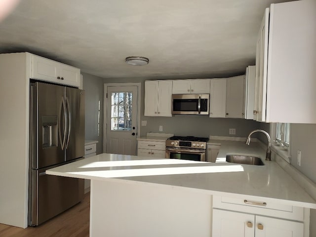 16 Fyffe Ave, Cranston, RI 02920 - kitchen featuring appliances with stainless steel finishes, a peninsula, light countertops, white cabinets, and wood finished floors