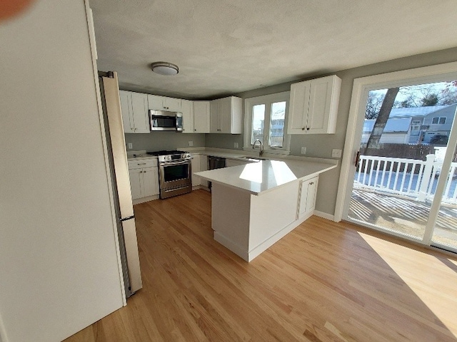 16 Fyffe Ave, Cranston, RI 02920 - kitchen with stainless steel appliances, a peninsula, light wood-type flooring, light countertops, and white cabinets