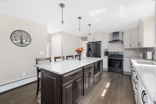 32 Susan Dr, Cumberland, RI 02864 - kitchen with black electric range, wall chimney exhaust hood, stainless steel fridge, a kitchen breakfast bar, and a baseboard heating unit