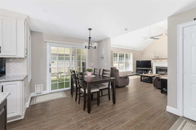 32 Susan Dr, Cumberland, RI 02864 - dining room with dark wood-style flooring, a chandelier, vaulted ceiling, a ceiling fan, and a glass covered fireplace