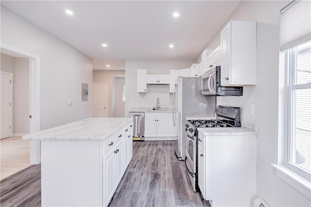15 Wendell St, Providence, RI 02909 - kitchen with stainless steel appliances, light wood-style floors, white cabinetry, a kitchen island, and recessed lighting