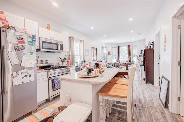 15 Wendell St, Providence, RI 02909 - kitchen featuring stainless steel appliances, a breakfast bar, light wood-style flooring, white cabinets, and healthy amount of natural light