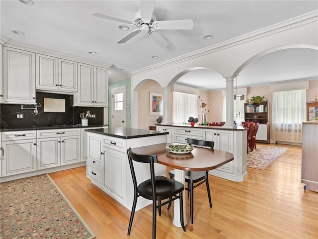 173 Gaskill St, Woonsocket, RI 02895 - kitchen featuring ornate columns, ornamental molding, dark countertops, a ceiling fan, and light wood-style flooring