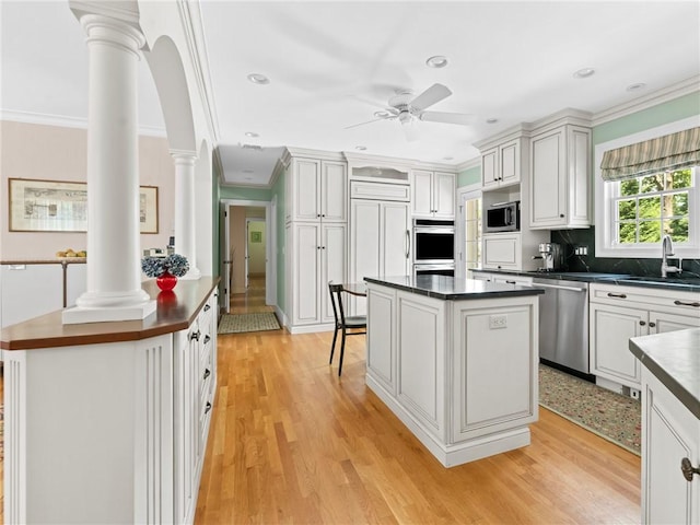 173 Gaskill St, Woonsocket, RI 02895 - kitchen with decorative columns, stainless steel appliances, dark countertops, crown molding, and a center island
