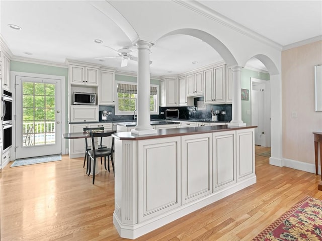 173 Gaskill St, Woonsocket, RI 02895 - kitchen with decorative columns, stainless steel microwave, healthy amount of natural light, dark countertops, and ornamental molding