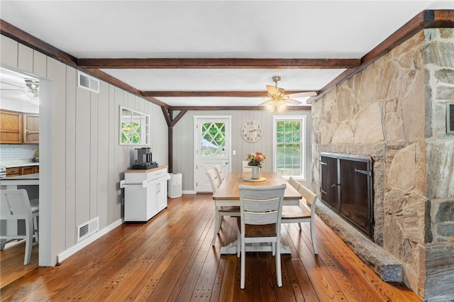 85 N Cobble Hill Rd, Warwick, RI 02886 - dining area featuring a ceiling fan, wood-type flooring, a fireplace with raised hearth, and beamed ceiling