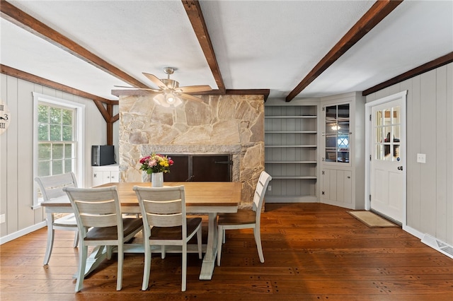 85 N Cobble Hill Rd, Warwick, RI 02886 - dining area featuring hardwood / wood-style flooring, a ceiling fan, beamed ceiling, a stone fireplace, and a decorative wall