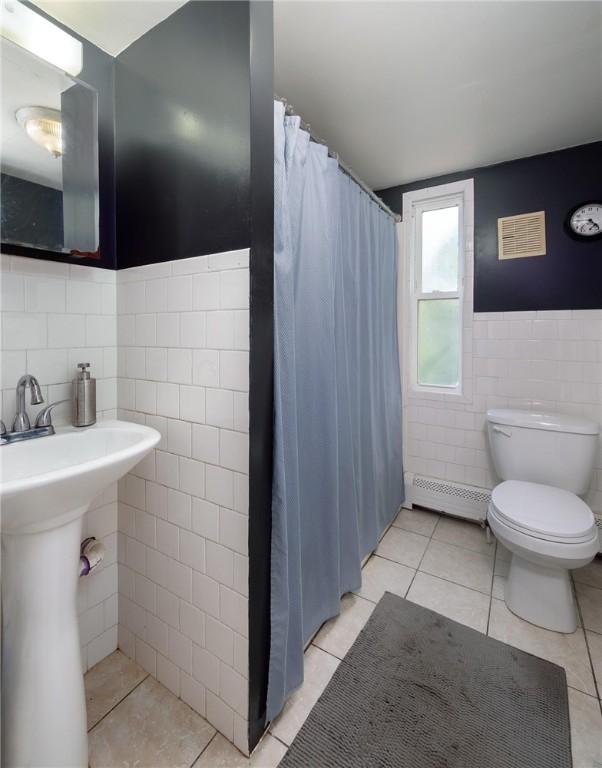 61 Penn St, Providence, RI 02909 - bathroom featuring tile walls, a baseboard radiator, curtained shower, tile patterned flooring, and wainscoting