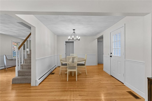 188 Reynolds Ave, Warwick, RI 02889 - dining area featuring baseboard heating, a chandelier, light wood-style floors, wainscoting, and stairway