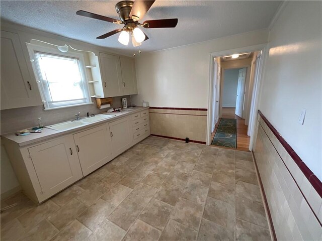 94 Alvin St, Warwick, RI 02886 - kitchen featuring ceiling fan, wainscoting, white cabinets, light countertops, and a textured ceiling