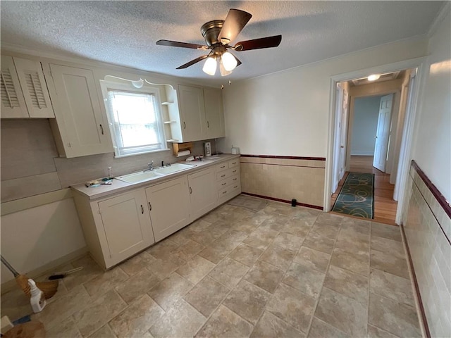 94 Alvin St, Warwick, RI 02886 - kitchen with a wainscoted wall, a textured ceiling, white cabinets, a ceiling fan, and light countertops