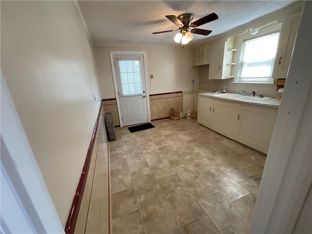 94 Alvin St, Warwick, RI 02886 - kitchen with wainscoting, white cabinets, ceiling fan, crown molding, and light countertops