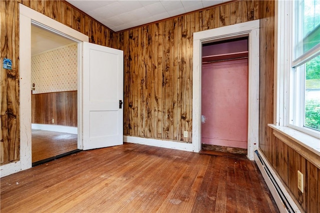 3442 Flat River Rd, Coventry, RI 02816 - unfurnished bedroom with baseboard heating, wood-type flooring, wood walls, and a closet