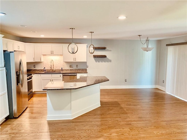 724 Centerville Rd Unit 6, Warwick, RI 02886 - kitchen with stainless steel appliances, a kitchen island, white cabinetry, dark stone counters, and decorative light fixtures