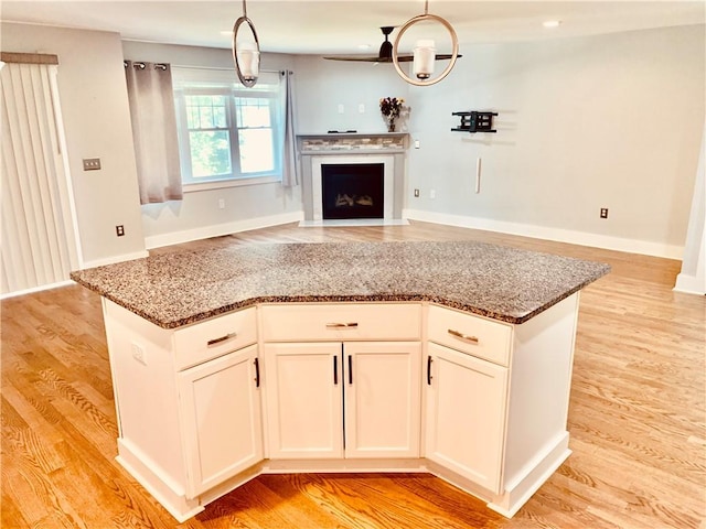 724 Centerville Rd Unit 6, Warwick, RI 02886 - kitchen featuring open floor plan, stone countertops, light wood-type flooring, a fireplace with flush hearth, and a kitchen island