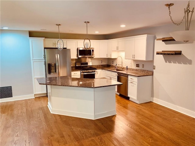 724 Centerville Rd Unit 6, Warwick, RI 02886 - kitchen featuring appliances with stainless steel finishes, a center island, white cabinets, hanging light fixtures, and dark stone counters